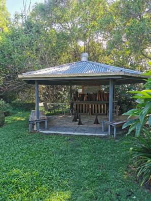 A gazebo with a table and benches in a grassy area

Description automatically generated