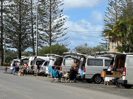 A group of people sitting in a row of white vans

AI-generated content may be incorrect.